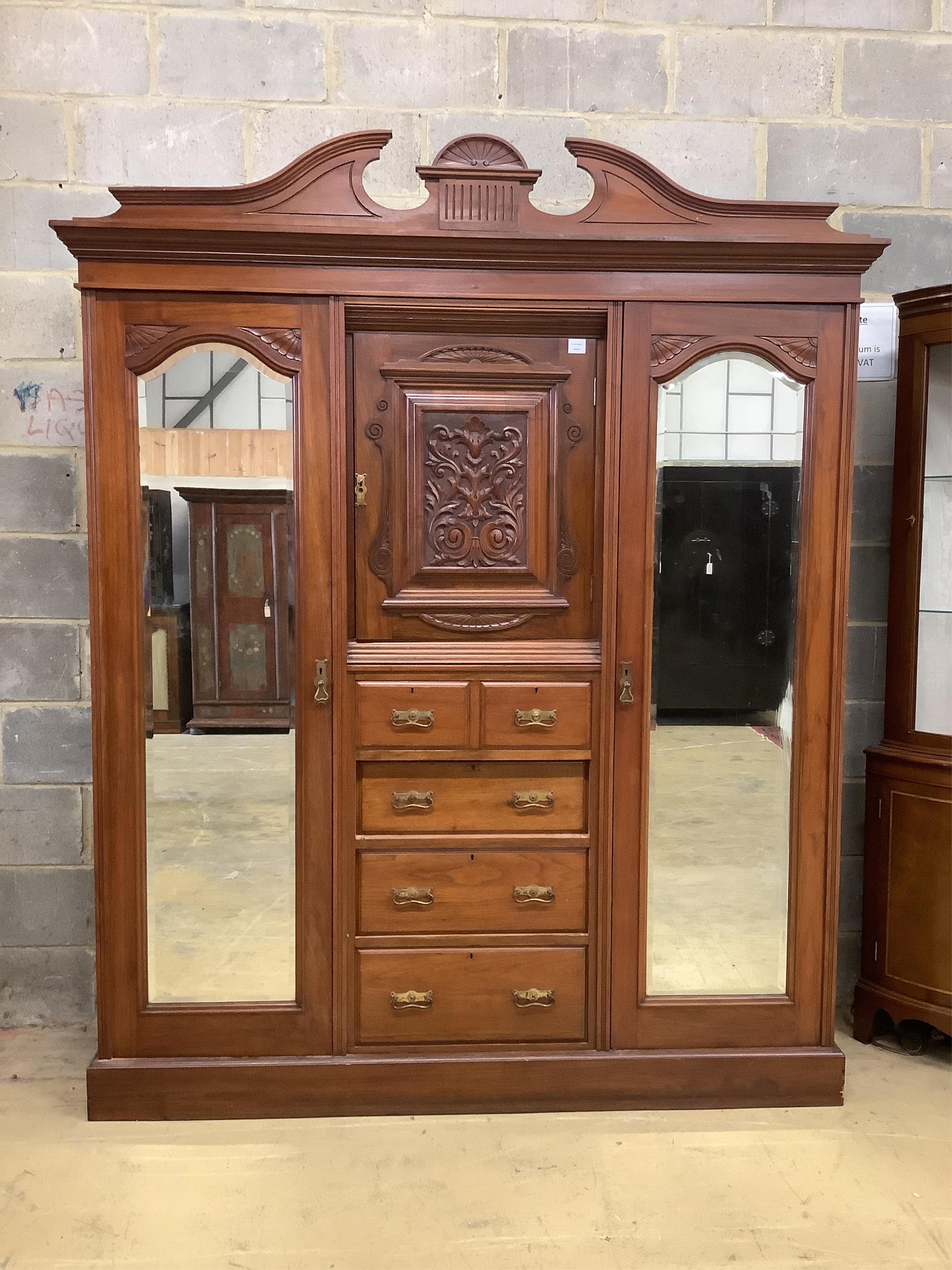 A late Victorian carved walnut mirrored compactum wardrobe, width 186cm, depth 56cm, height 227cm. Condition - good